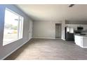 Inviting living room with wood-look tile flooring, a bright, large window, and open access to the kitchen at 3085 Sw 131St Place Rd, Ocala, FL 34473