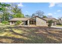 Charming single-story home with stone facade, large windows, mature trees, and a well-manicured lawn at 4425 Se 2Nd Pl, Ocala, FL 34471