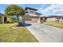 Well-maintained lawn leads to a two-car garage with a landscaped garden and accent tree at 7234 Sw 91St Ct, Ocala, FL 34481