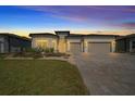 Charming home features a well-manicured lawn, colorful plants, and a brick paver driveway illuminated by evening lights at 8825 Sw 57Th Place Rd, Ocala, FL 34481