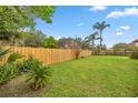 A fenced in backyard with a palm tree, lush greenery, and well-maintained lawn at 1000 Woodward Oaks Cir, Eustis, FL 32726