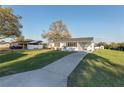 Wide angle shot of a well-kept single story home featuring a long drive and covered carport at 10495 Sw 100Th Ave, Ocala, FL 34481