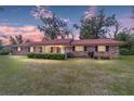 Charming brick home features a vibrant red roof and a welcoming front porch at dusk at 1300 Ne 53Rd St, Ocala, FL 34479