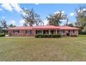 Charming brick home with a red roof, covered porch, and lush landscaping at 1300 Ne 53Rd St, Ocala, FL 34479