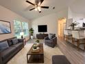 Cozy living room featuring a comfortable gray sofa and chair, with a ceiling fan and bright natural light at 17710 Sw 48Th Pl, Dunnellon, FL 34432