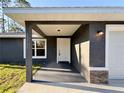 Welcoming front porch with stone accents, modern lighting fixtures, and elegant white front door, setting a stylish tone at 17710 Sw 48Th Pl, Dunnellon, FL 34432