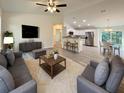 Spacious living room featuring modern gray sofas, a soft rug, and a seamless view into the bright kitchen area at 17710 Sw 48Th Pl, Dunnellon, FL 34432
