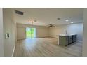 Open-concept living room with kitchen island, wood-look floors, and sliding glass doors to the backyard at 31 Juniper Pass Ln, Ocala, FL 34480