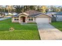 Charming one-story home with a well-manicured lawn and an attached two-car garage at 5758 Nw 63Rd Pl, Ocala, FL 34482