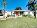 Charming single-story home with a well-manicured lawn, cute furniture set, and a striking orange front door at 634 Nw 56Th Ave, Ocala, FL 34482