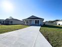 Inviting single-story home featuring a well-kept lawn and a spacious concrete driveway at 6584 Se 108Th Ln, Belleview, FL 34420