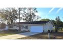 Inviting single-story home featuring an attached garage and neutral siding, set against a backdrop of mature trees at 8516 Sw 105Th Pl, Ocala, FL 34481
