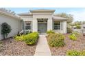 Inviting entryway showcasing a well-maintained walkway, lush landscaping, and a charming front door at 8961 Se 130Th Loop, Summerfield, FL 34491