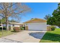 Home with a large two-car garage, complemented by mature landscaping and a clear blue sky at 9305 Bahia Track Way, Ocala, FL 34472