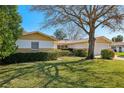 Well-maintained home exterior with lush lawn and landscaping, complemented by a sunny, clear sky at 9305 Bahia Track Way, Ocala, FL 34472