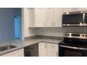 Well-equipped kitchen boasts stainless steel appliances, granite countertops, and sleek white cabinetry at Tbd Malauka Rd, Ocklawaha, FL 32179