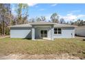 A view of the home's rear exterior shows a covered patio and a sliding glass door entrance at 12876 Se 42Nd Ct, Belleview, FL 34420