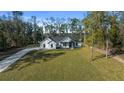 Aerial view showcasing the home's setting, long driveway, spacious front yard, and wooded surroundings at 13751 Sw 49Th Pl, Ocala, FL 34481