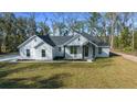 Stylish single-story home featuring crisp white exterior, dark gray roof, and lush green lawn at 13751 Sw 49Th Pl, Ocala, FL 34481