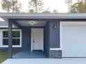 Inviting entryway with a white front door, stone accents, and attached garage at 3896 Sw 177Th Ter, Dunnellon, FL 34432