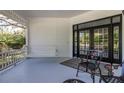 Covered porch with black metal chairs, porch swing and black framed double doors leading inside at 8380 Se 7Th Avenue Rd, Ocala, FL 34480
