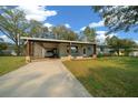 Charming single-story home with a carport, well-maintained lawn, and a long driveway, set under a blue sky with scattered clouds at 8917 Sw 101St Ln, Ocala, FL 34481