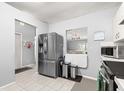 Open kitchen with stainless steel refrigerator, tile floor, and a view into the living room at 9365 Sw 89Th Ter # F, Ocala, FL 34481