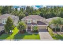Attractive two-story home featuring a brick driveway, lush green lawn, and mature palm trees at 1073 Vinsetta Cir, Winter Garden, FL 34787
