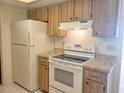 Bright kitchen featuring white appliances, wood cabinets, and stone countertops at 11255 Sw 76Th Ter, Ocala, FL 34476