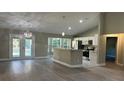 Open-concept living space with wood flooring, pendant lighting, and a kitchen island perfect for entertaining at 114 Bay Dr, Ocklawaha, FL 32179