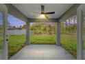 Covered outdoor patio with a ceiling fan, concrete flooring, and views of the private backyard and surrounding nature at 114 Bay Dr, Ocklawaha, FL 32179