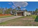 Exterior shows driveway leading to two car garage with green lawn and fence at 14 Hemlock Loop Court, Ocala, FL 34472