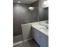 Modern bathroom featuring gray tile shower, white vanity, and a sleek, frameless shower screen at 27 Laurel Ct, Ocala, FL 34472