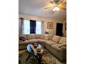 Comfortable living room featuring a large sectional sofa, a ceiling fan, and natural light from the curtained windows at 310 Oak Track Dr, Ocala, FL 34472