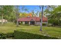 Charming home with a red tiled roof and lush green lawn, surrounded by mature trees and landscaping at 411 Sw 38Th St, Ocala, FL 34471