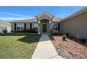 Inviting front entrance with a pathway, complemented by dark shutters and manicured landscaping at 5086 Sw 91St St, Ocala, FL 34476