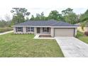 Charming single-story home with a well-manicured lawn and attached garage at 6047 Sw 128Th Street Rd, Ocala, FL 34473