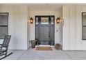 Elegant front door with glass panels and sidelights, complemented by stylish lighting fixtures and plants at 7432 Ne 26Th Ave, Ocala, FL 34479