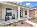 Charming front porch with rocking chairs and a view of the home's inviting entrance and landscaping at 7432 Ne 26Th Ave, Ocala, FL 34479