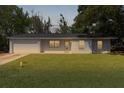 Charming single-story home with a well-manicured lawn and attached garage at twilight at 9607 Se 122Nd Pl, Belleview, FL 34420
