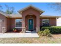 Inviting home featuring a covered entryway, decorative stone accents, and lush landscaping enhancing the curb appeal at 16272 Se 89Th Ct, Summerfield, FL 34491