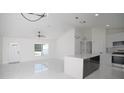 Spacious living room with vaulted ceilings, fan, and an open layout to a modern kitchen with a center island at 19 Juniper Pass, Ocala, FL 34480
