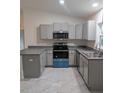 A well-equipped kitchen featuring gray cabinets, stainless steel appliances, and tile flooring at 261 Locust Pass Loop, Ocala, FL 34472
