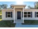 Close up of home's front door featuring a covered entry and attractive black shutters at 29 Fisher Ter, Ocklawaha, FL 32179
