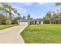 Beautiful single-story home featuring a manicured lawn and a long driveway leading to a two-car garage at 5620 Sw 172Nd Loop, Ocala, FL 34473