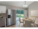 Cozy dining area featuring a round table, stylish chairs, adjacent to a stainless-steel refrigerator, and sliding glass doors at 59 Fisher Ct, Ocklawaha, FL 32179