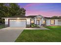Dusk view of a well-kept single-story house with an attached two-car garage at 8330 Se 161St St, Summerfield, FL 34491