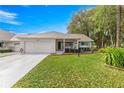 Inviting single-story home featuring an attached garage, colorful turquoise shutters, and a well-maintained lawn at 8710 Sw 91St Pl # E, Ocala, FL 34481