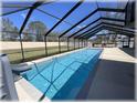Enclosed pool area with a long rectangular pool, patio, and a clear blue sky above at 6307 Se 8Th Ln, Ocala, FL 34472