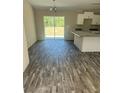 Open kitchen with gray wood flooring, modern lighting, and bright sliding door to the backyard at 734 Nw 57Th Ave, Ocala, FL 34482